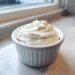 A white ramekin filled high with freshly made, fluffy creamy horseradish sauce.