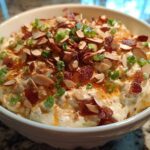 A bowl of creamy Neiman Marcus Dip topped generously with sliced almonds, crumbled bacon, and green onions.