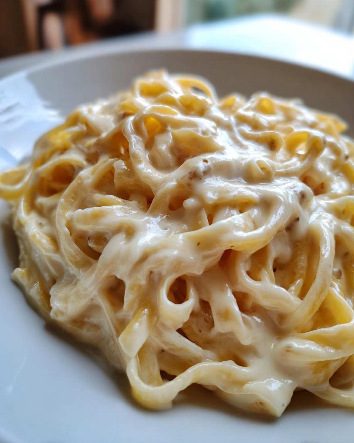 Close-up of fettuccine noodles generously coated in rich, creamy homemade alfredo sauce.