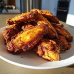 A pile of perfectly crispy, golden-brown seasoned chicken wing pieces stacked on a white plate.