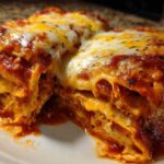 Close-up of a serving of easy chicken enchiladas smothered in red sauce and melted cheese.