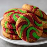 Close-up of stacked pinwheel cookies featuring swirling red and green sugar decorations.