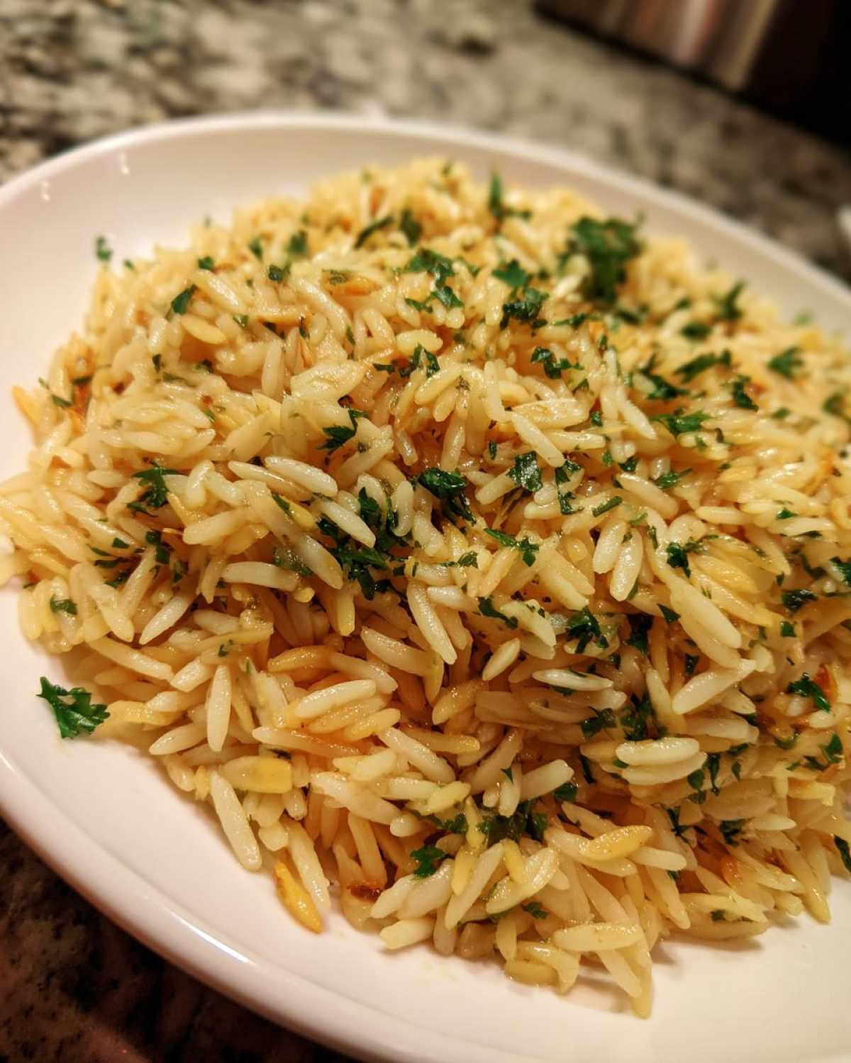 Close-up of fluffy, golden-brown rice pilaf garnished generously with fresh chopped parsley.