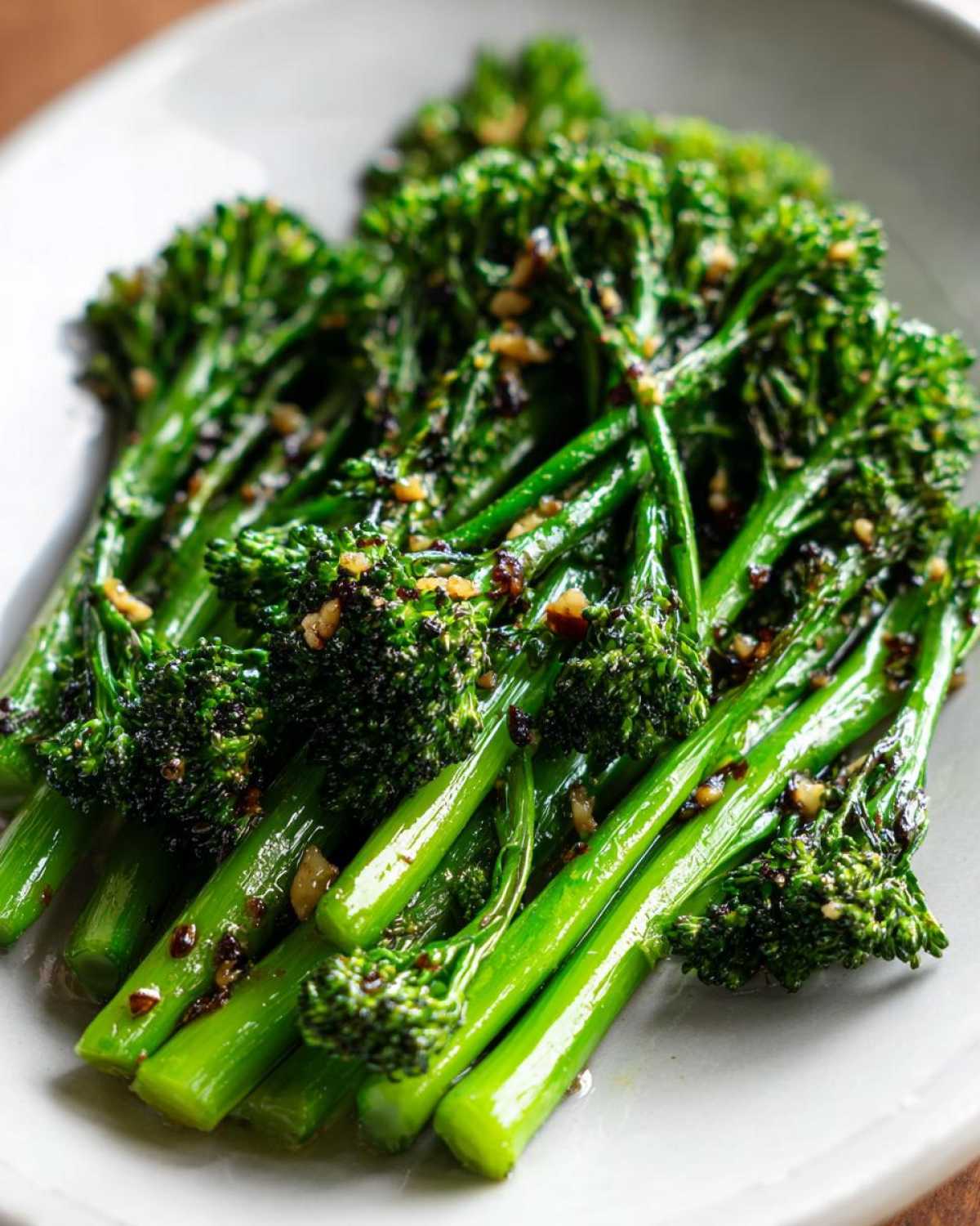 Close-up of bright green, tender-stemmed broccolini tossed with garlic and lemon sauce.