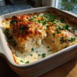 Close-up of a creamy Garlic Parmesan Chicken Bake, showing browned cheese topping and moist chicken submerged in sauce.