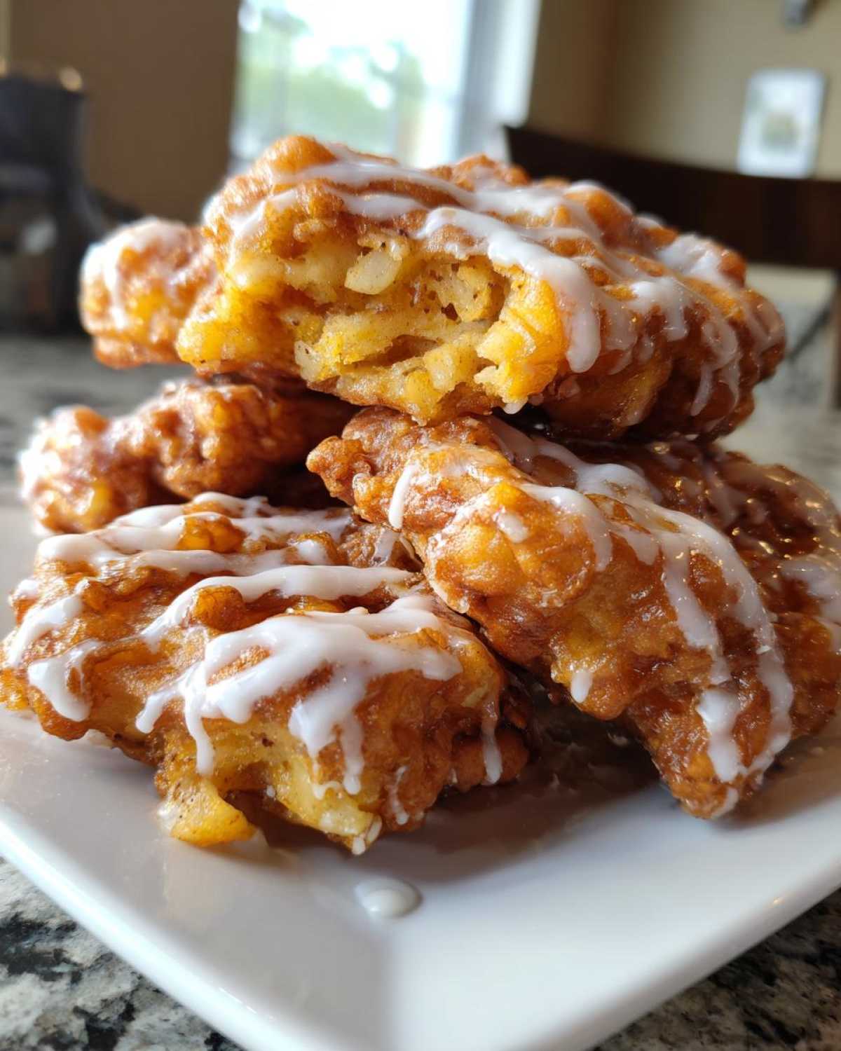 A close-up stack of golden-brown, glazed apple fritter pieces showing the chunky apple filling inside.