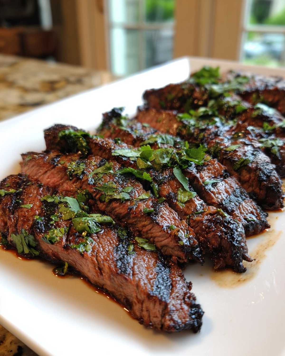 Slices of perfectly grilled steak, glistening with marinade and topped with fresh cilantro, ready to eat.