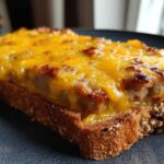 Close-up of a slice of toast topped with savory meat mixture and melted cheddar cheese, part of the hanky panky recipe.