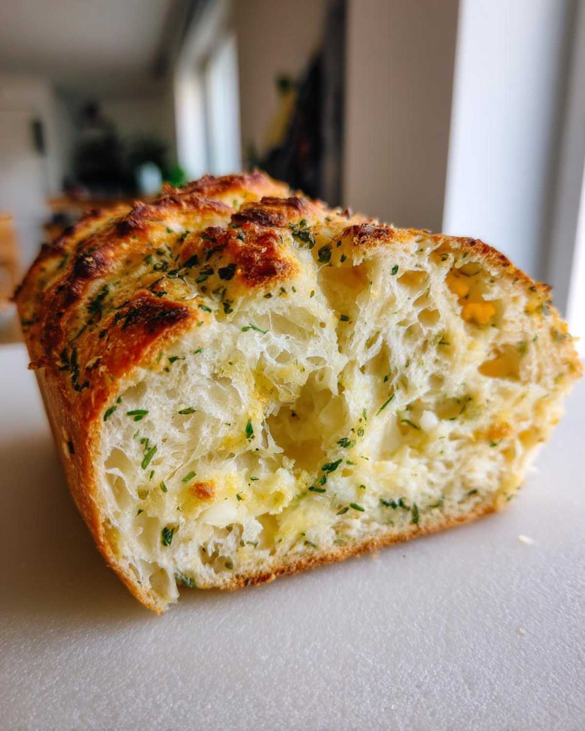 Cross-section view showing the airy crumb and melted cheese pockets in the Italian herb and cheese bread loaf.