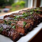 Close-up of perfectly grilled and sliced carne asada, glistening and topped with fresh cilantro, showcasing the results of the carne asada marinade.