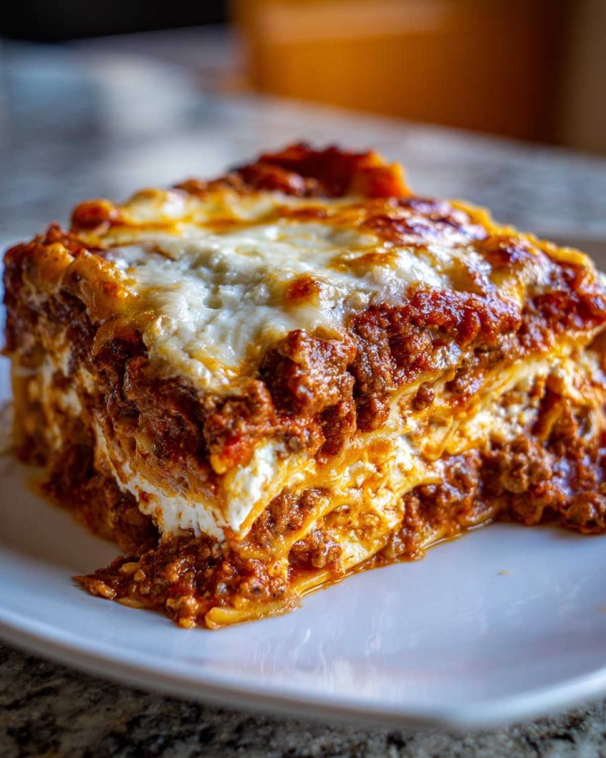 A thick, layered slice of Lasagna with Cottage Cheese served on a white plate, featuring rich meat sauce and melted cheese.