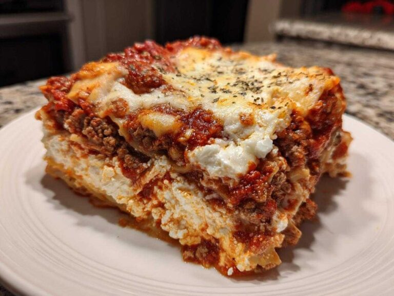 A thick, layered slice of Lasagna with Cottage Cheese on a white plate, topped with melted cheese and herbs.