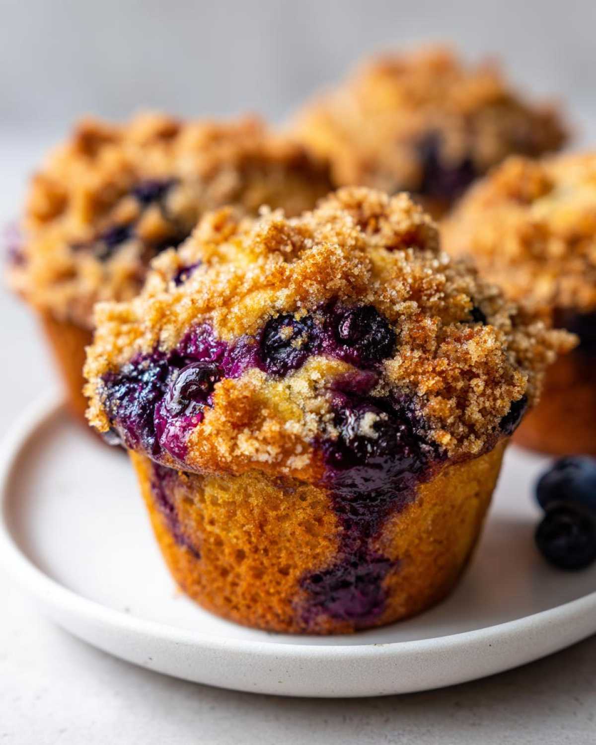 Close-up of a moist blueberry muffin topped with brown sugar streusel, showing burst blueberries.