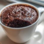 Close-up of a moist chocolate mug cake topped with chocolate chips, ready to eat.