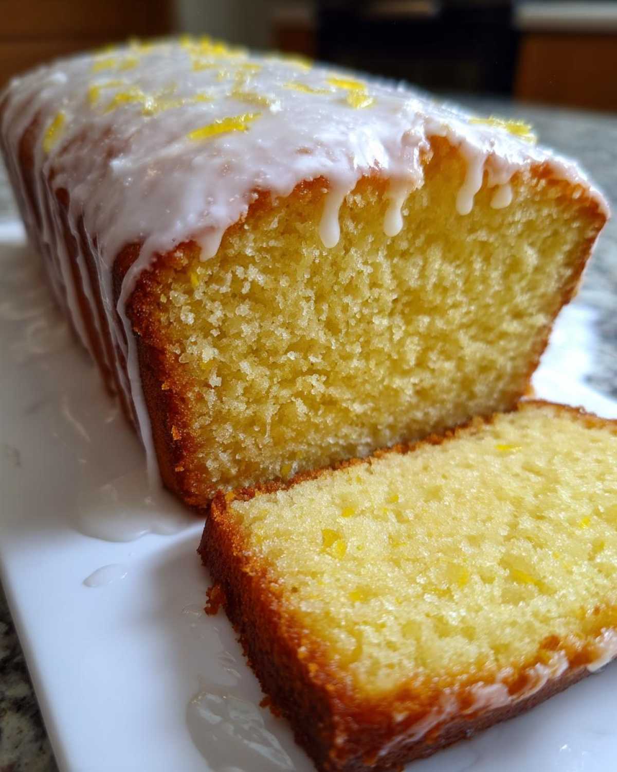 Close-up of a moist lemon pound cake, sliced, showing the crumb texture and thick lemon glaze.