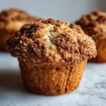 Close-up of a moist oatmeal muffin featuring a thick, sugary cinnamon crumb topping.