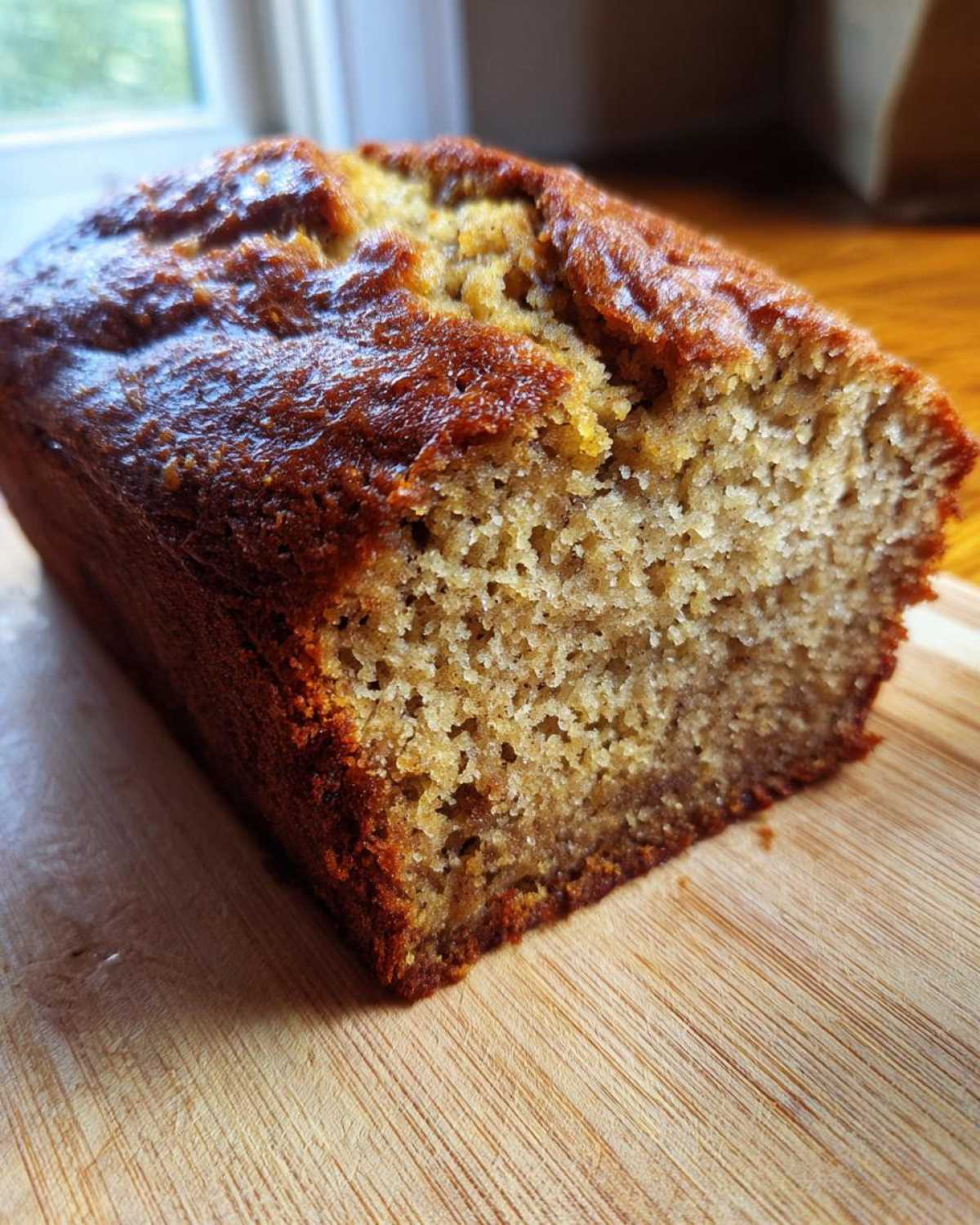 Close-up of a moist slice of freshly baked sugar free banana bread loaf on a wooden cutting board.