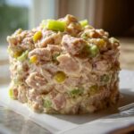 A molded serving of creamy ham salad recipe with visible chunks of ham, celery, and yellow relish.