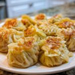 Close-up of freshly pan-fried Traditional Chinese Dumplings arranged on a white plate.