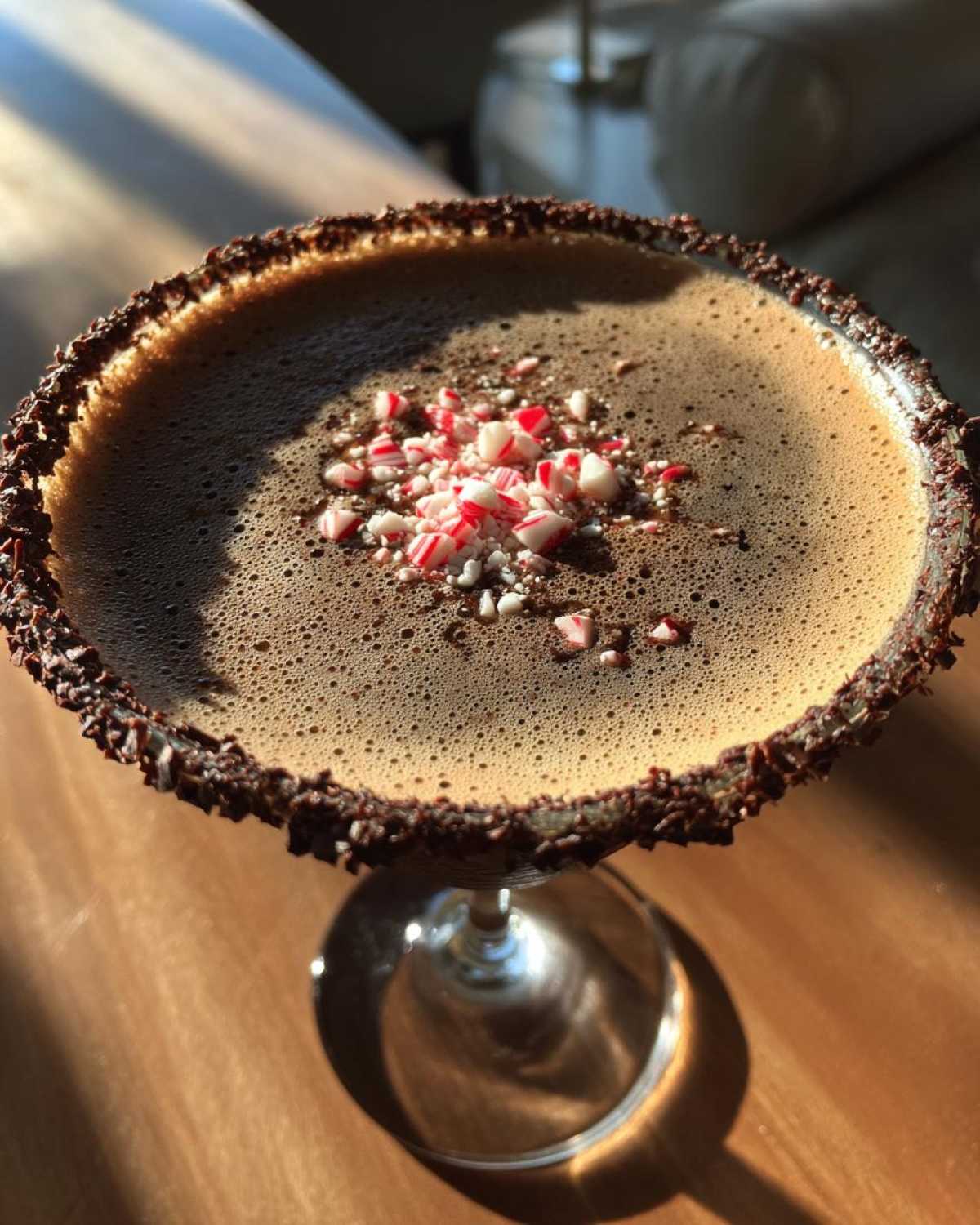 Close-up of a peppermint espresso martini with a chocolate rim and crushed candy canes on top.