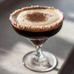 A rich, dark peppermint espresso martini garnished with crushed candy canes and chocolate shavings.