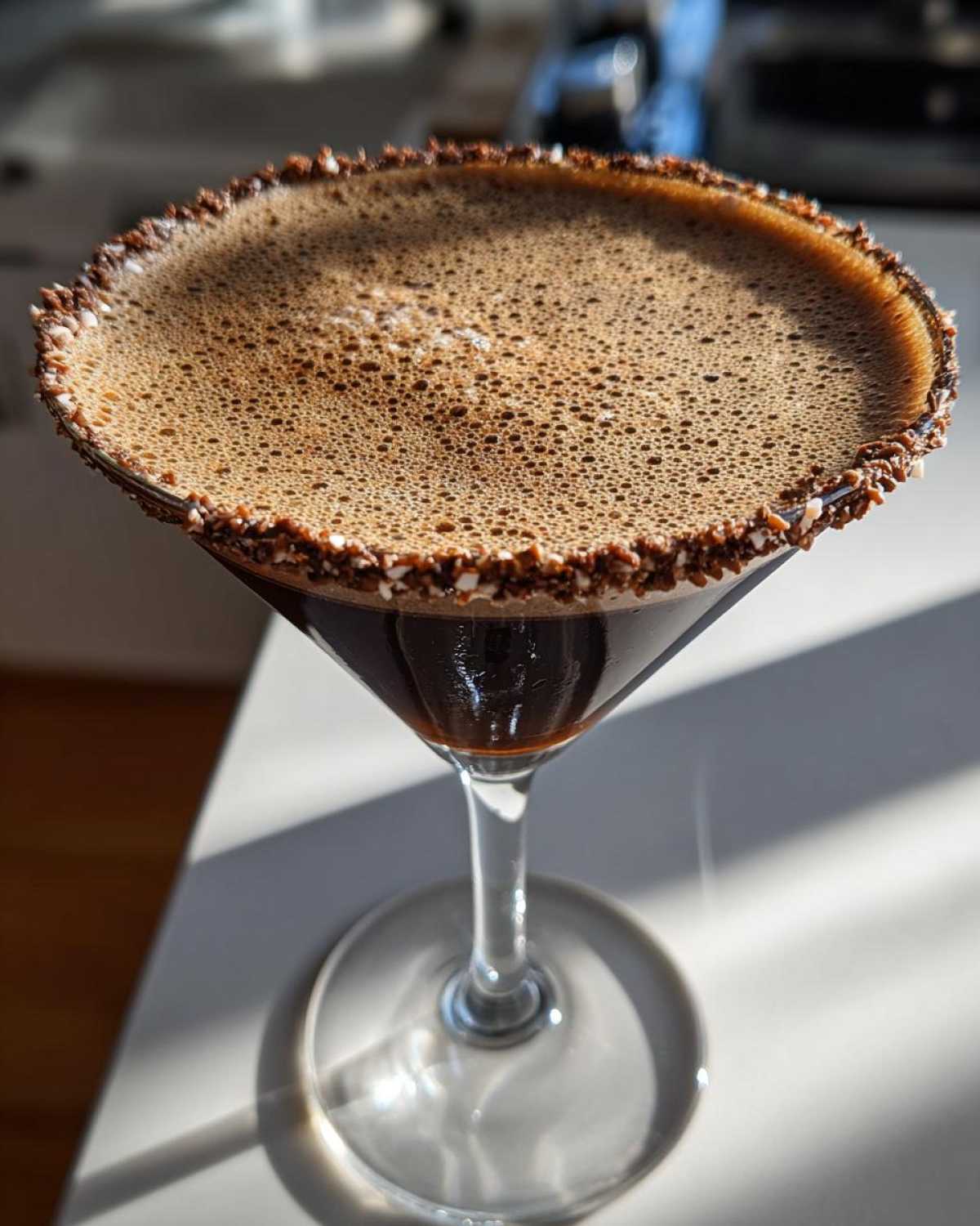 Close-up of a finished peppermint espresso martini in a martini glass with a chocolate and peppermint rim.