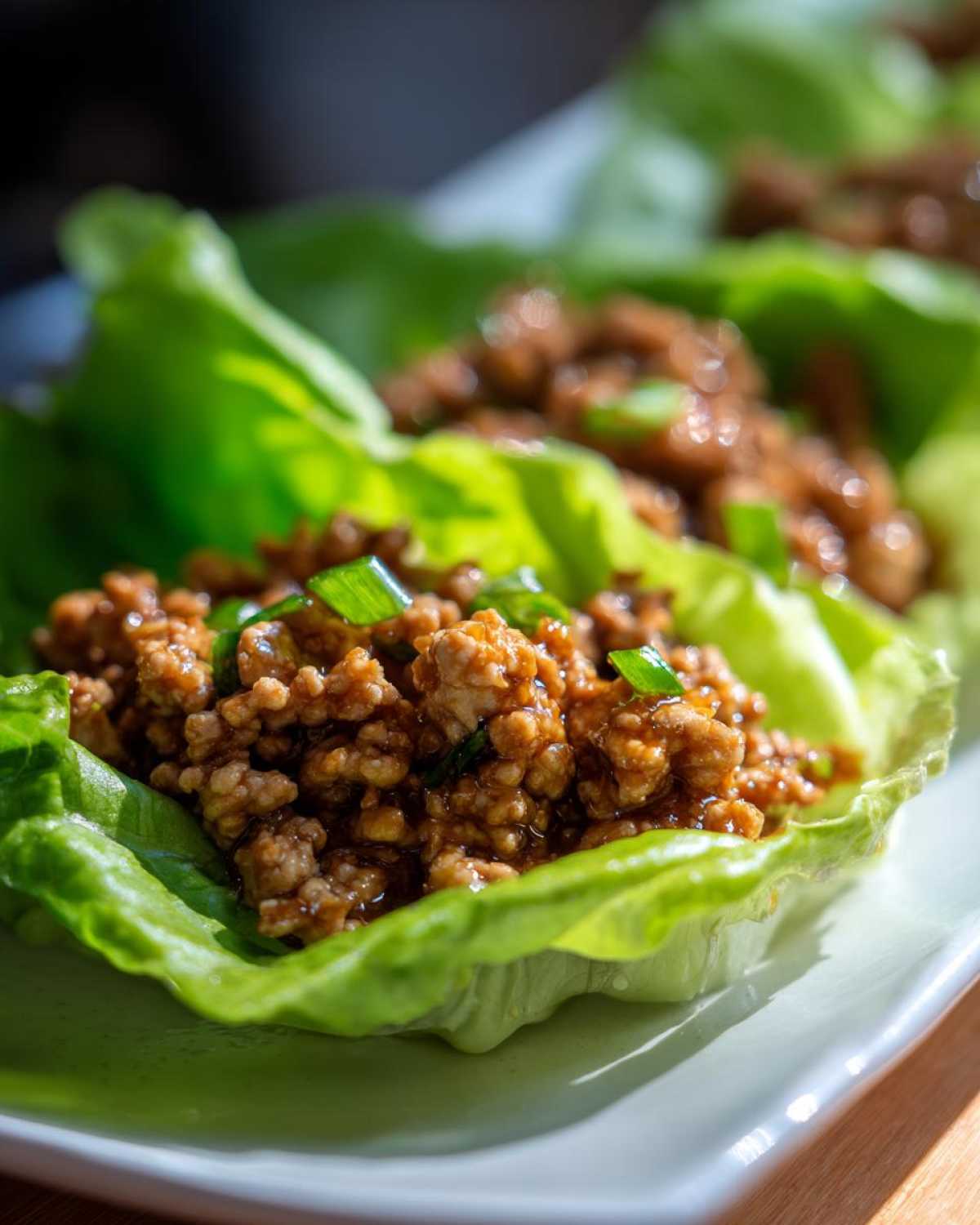A close-up of delicious chicken lettuce wraps filled with savory ground chicken mixture and topped with green onions.