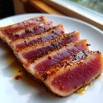 Four slices of perfectly seared Ahi tuna steak showing a rare, deep red center, seasoned with spices from the MARINADE FOR TUNA STEAK.
