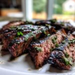 Close-up of medium-rare sliced steak glistening with juices, topped with cilantro, showing the results of the carne asada marinade.