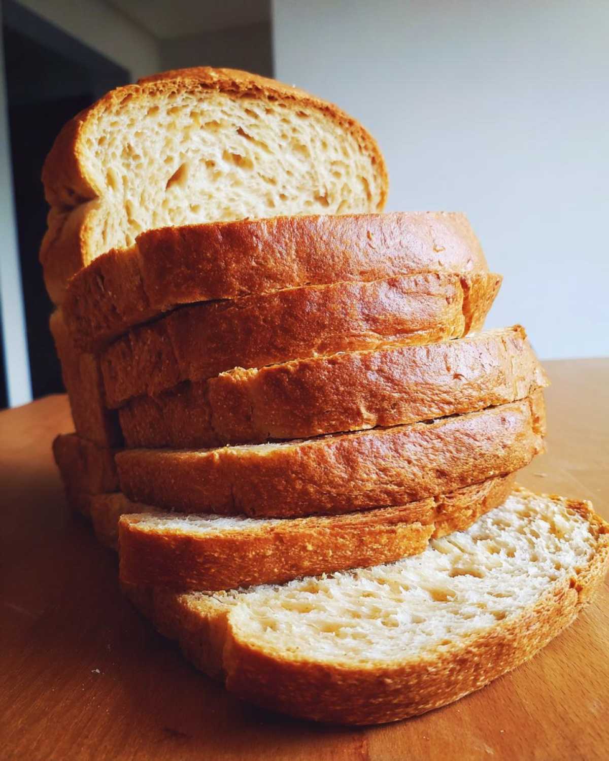 A stack of freshly sliced whole wheat bread showing a soft interior and golden-brown crust.