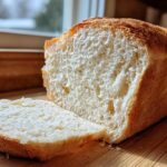 Close-up of a freshly baked loaf of condensed milk bread, sliced to show the soft, white crumb.