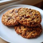 A stack of three golden brown, chewy oatmeal cookie treats studded with melted chocolate chips.