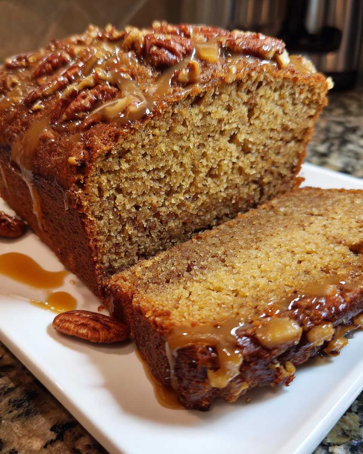 A close-up of sliced sweet alabama pecan bread topped with pecans and drizzled with caramel sauce.