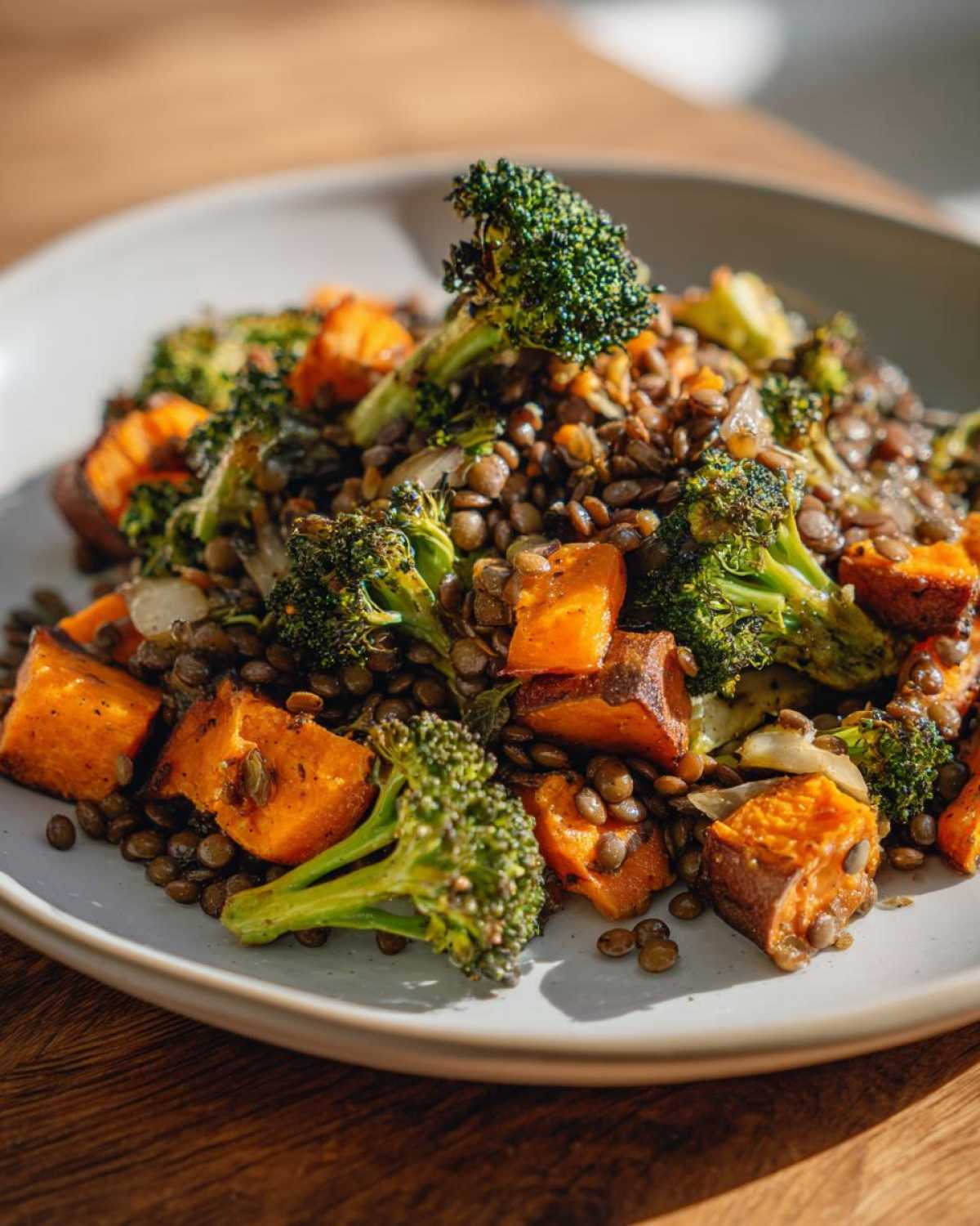 Close-up of a veggie lentil salad featuring brown lentils, roasted orange sweet potato chunks, and bright green broccoli florets.