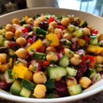Close-up of a colorful bean salad featuring chickpeas, kidney beans, cucumber, and yellow bell pepper.