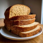 A stack of freshly sliced homemade whole wheat bread resting on a light gray plate.
