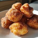 A close-up pile of golden Air Fryer Cinnamon Sugar Churro Bites coated heavily in sparkling sugar and cinnamon.