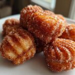 Close-up of several golden brown Air Fryer Cinnamon Sugar Churro Bites coated heavily in sparkling cinnamon sugar.