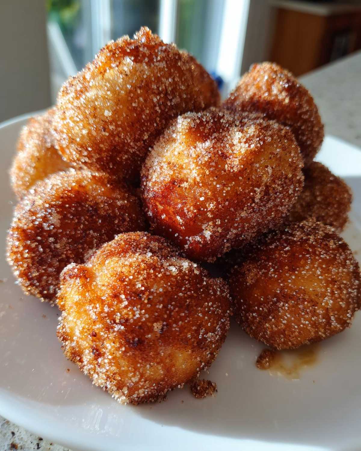 Close-up of a pile of golden brown Air Fryer Cinnamon Sugar Churro Bites coated heavily in sparkling cinnamon sugar.