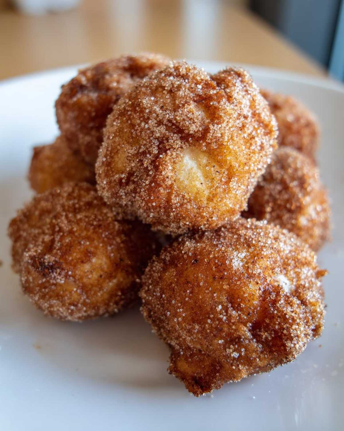 Close-up of golden brown Air Fryer Cinnamon Sugar Churro Bites coated heavily in cinnamon sugar.