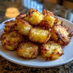 Close-up of golden brown, crispy Air Fryer Crispy Breakfast Potatoes with Paprika piled high on a white plate.
