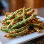A close-up of a pile of Air Fryer Crispy Tempura Green Beans with a light, golden-brown coating.