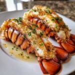 Two perfectly cooked Air Fryer Garlic Butter Lobster Tails, split and topped with melted butter and fresh parsley.