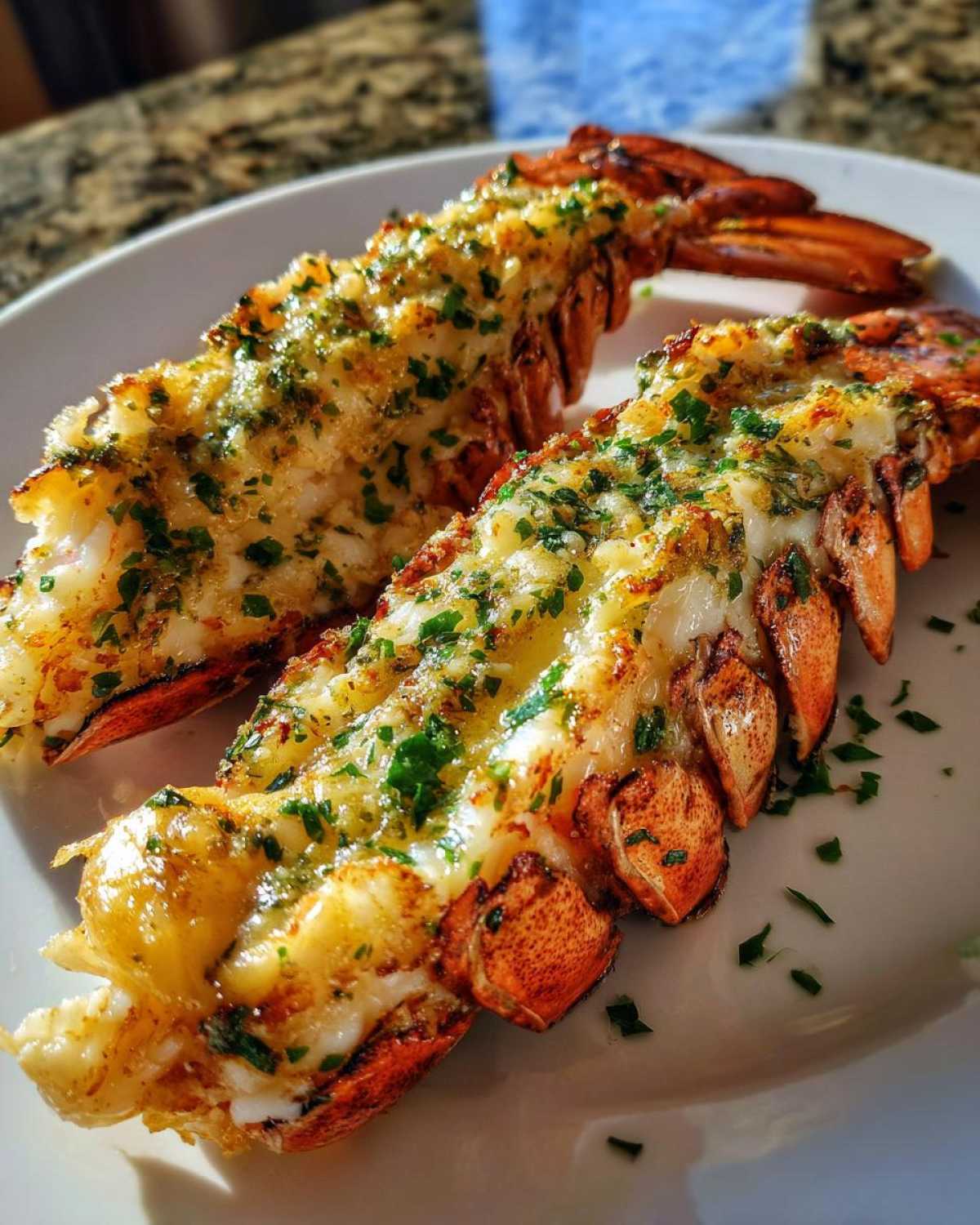 Two perfectly cooked Air Fryer Garlic Butter Lobster Tails, split and topped with melted garlic butter and fresh parsley.