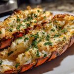 Two perfectly cooked Air Fryer Garlic Butter Lobster Tails, split open and topped with melted butter and fresh parsley.