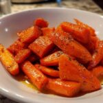 Bright orange, glazed carrots seasoned with herbs served in a white bowl, showcasing the Air Fryer Maple Glazed Carrots recipe.