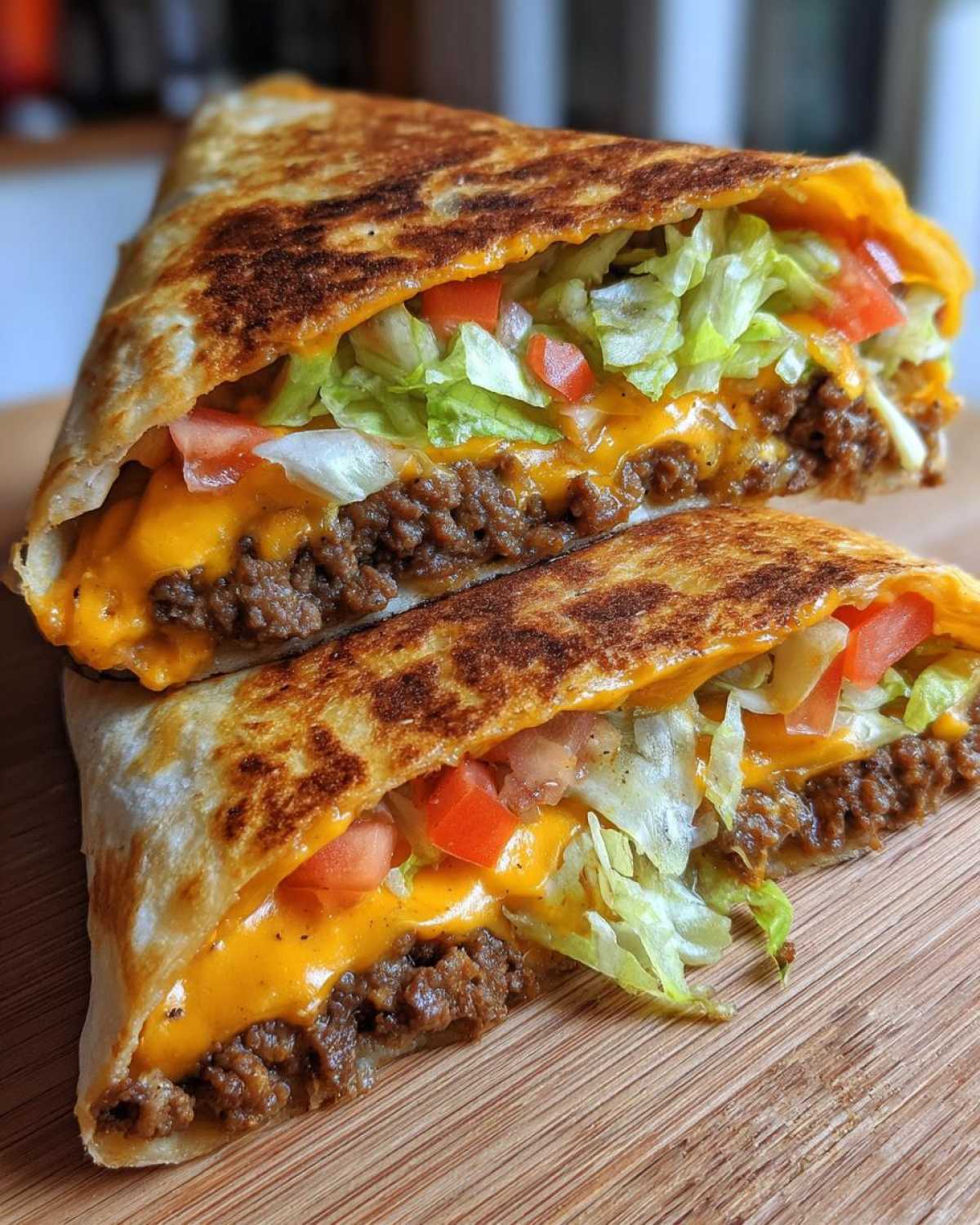 A perfectly grilled Copycat Taco Bell Crunchwrap Supreme cut in half, showing seasoned beef, melted cheese, lettuce, and tomatoes.