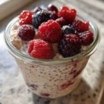 Close-up of Easy Berry Chia Overnight Oats topped with fresh raspberries, blueberries, and blackberries.