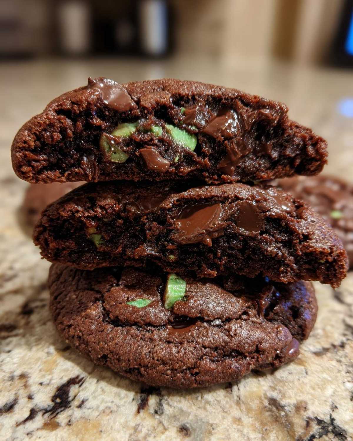 Close-up of three Gluten-Free Chocolate Mint Cookies stacked, showing the gooey melted chocolate chips and mint pieces inside.