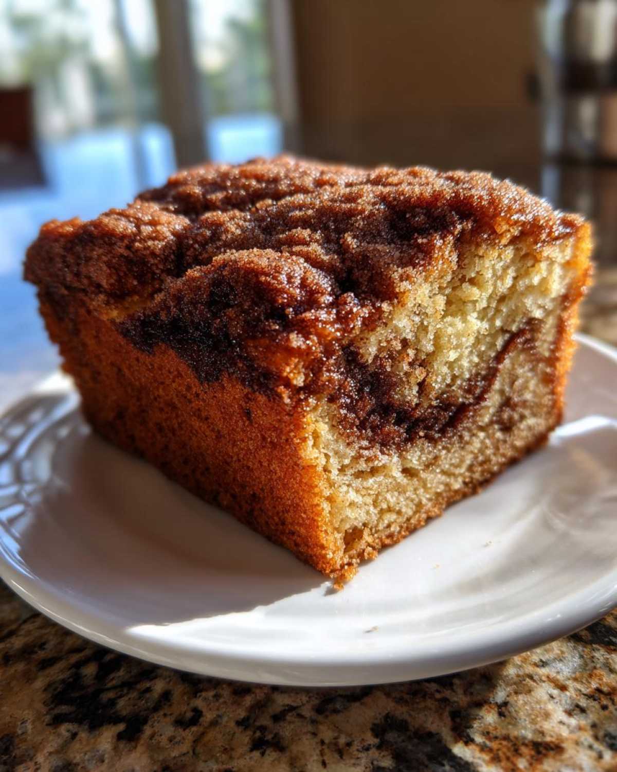 A close-up of a square slice of Gluten-Free Cinnamon Sugar Coffee Cake on a white plate.